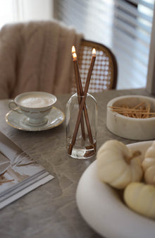 Filiżanka kawy w porcelanowej filiżance w towarzystwie delikatnych płomieni świecy Oliensa Eternal Copper Crystal. 