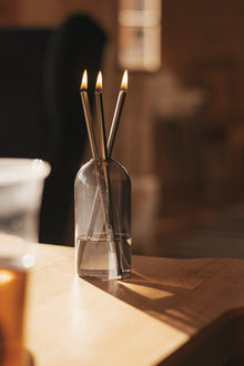 świeca oliensa eternal gold mist przeszyta światłem słonecznym. Podkreślony detal czystego szkła oraz metalu