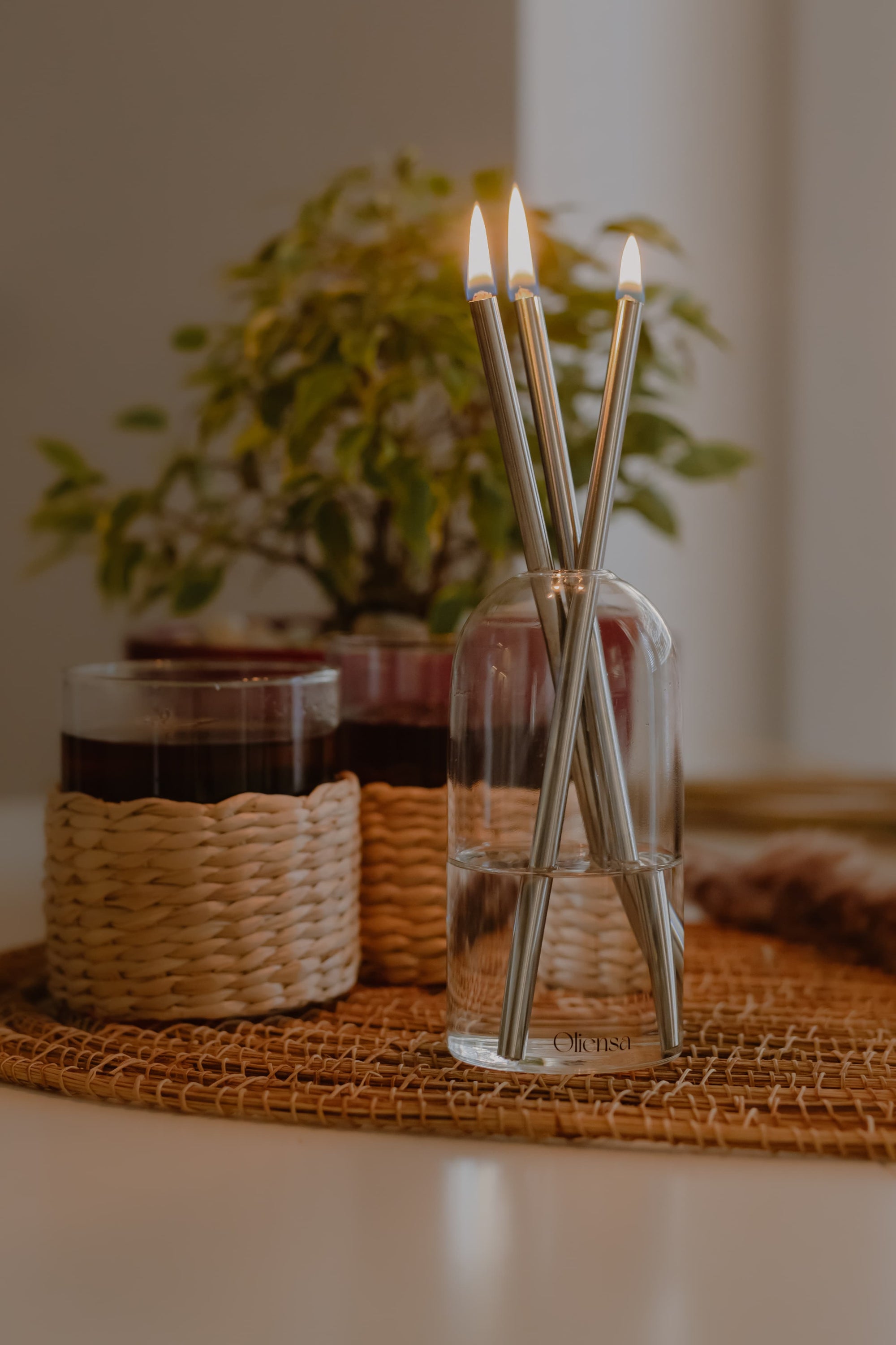 Świeca Oliensa Crystal Silver na stole w towarzystwie szklanek – subtelne światło i metaliczny połysk w eleganckiej, codziennej aranżacji.
