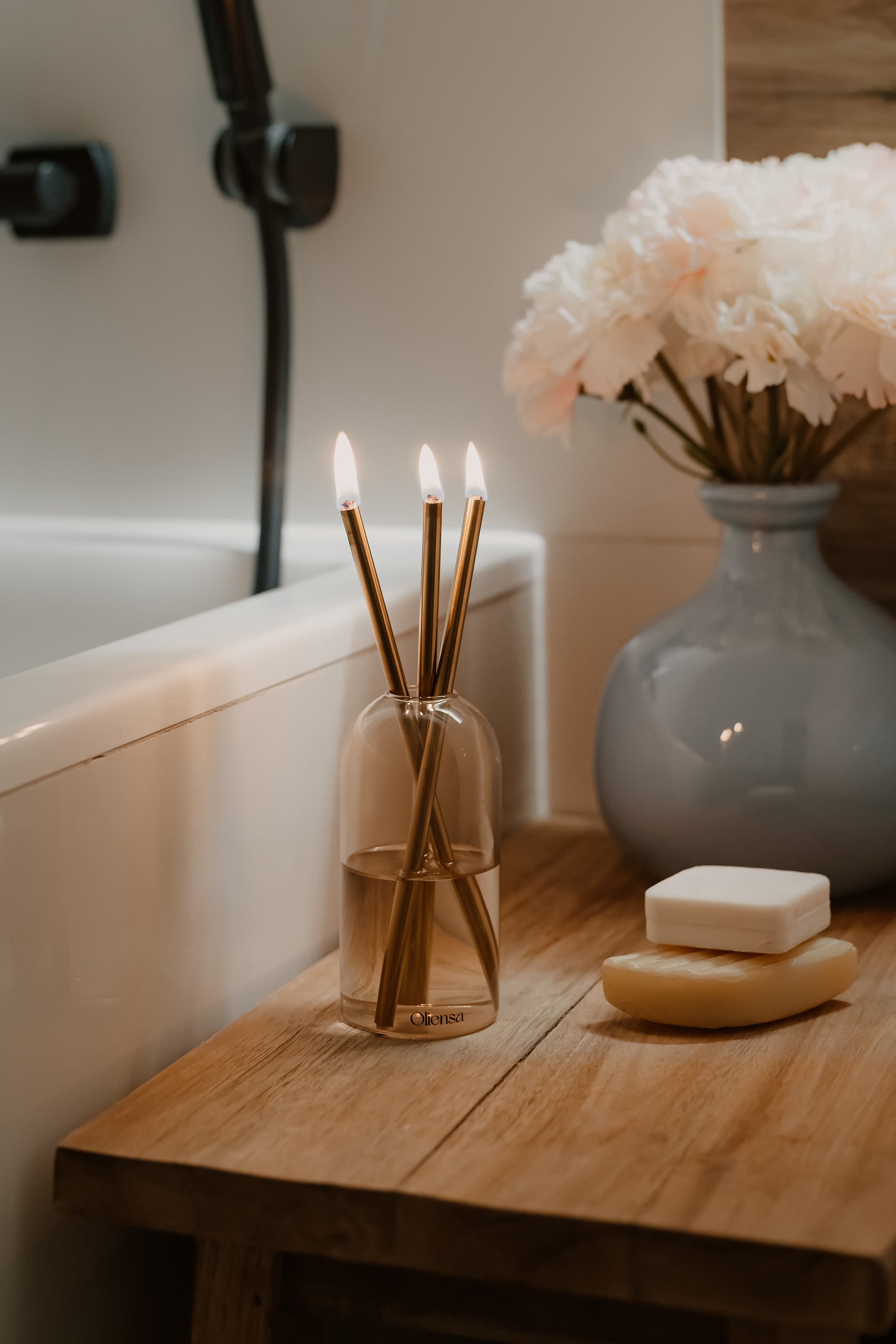Świeca Oliensa Sand Gold w łazience – ustawiona przy wannie i naturalnym mydle, tworzy atmosferę spokoju, intymności i luksusowego rytuału.