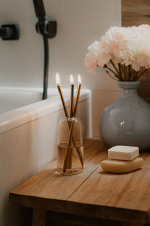 Świeca Oliensa Sand Gold w łazience – ustawiona przy wannie i naturalnym mydle, tworzy atmosferę spokoju, intymności i luksusowego rytuału.